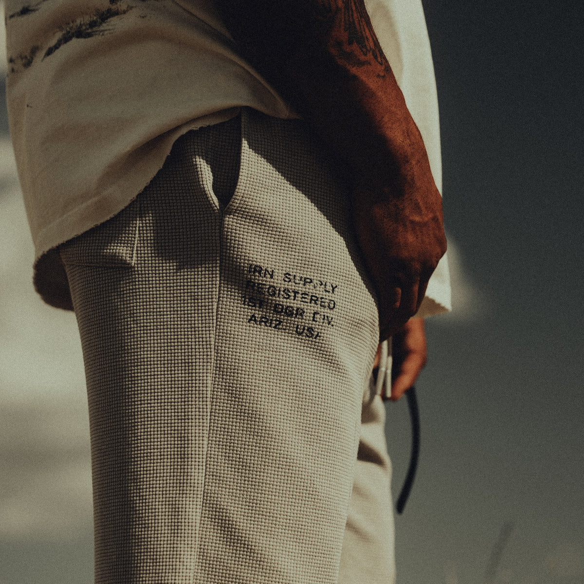 Detail of the cinder waffle sweatpant worn with the cream Iron Outlaw tee
