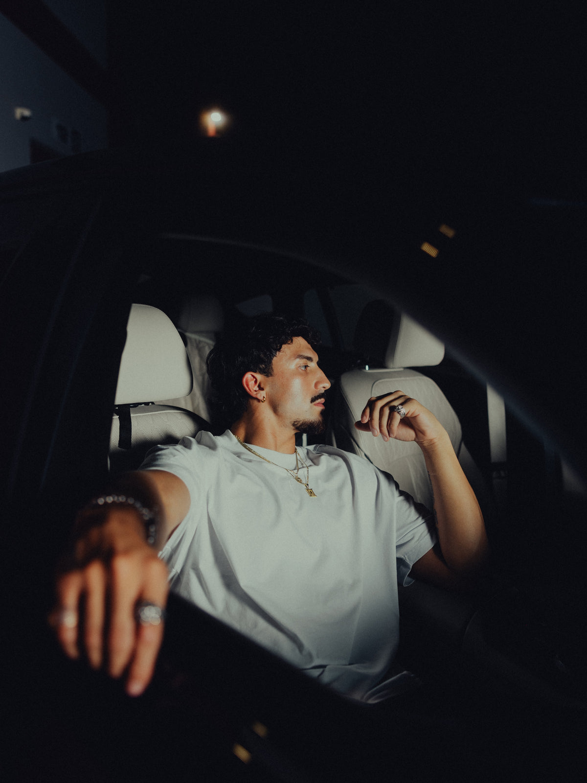 Model in the white classic crew tee seated in a car