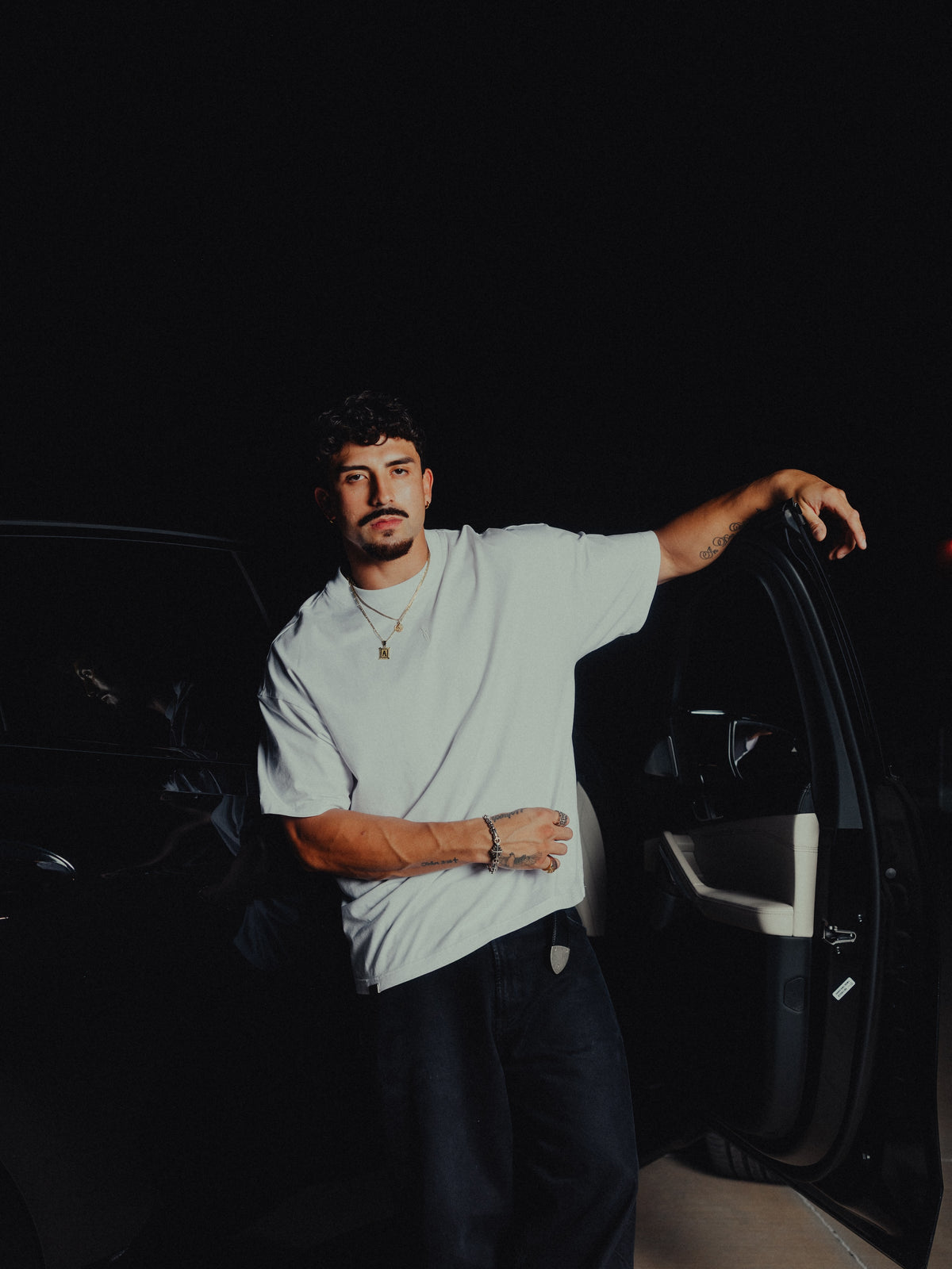 Model leaning on a car door in the white classic crew tee