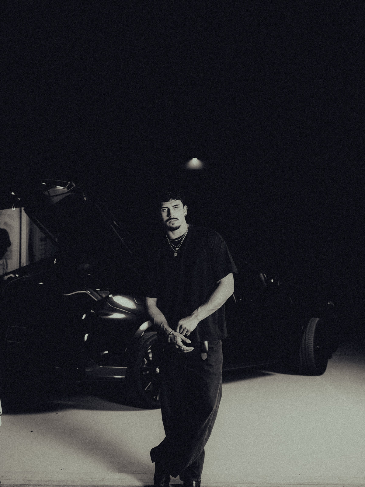 Model standing in a garage in the black classic crew tee