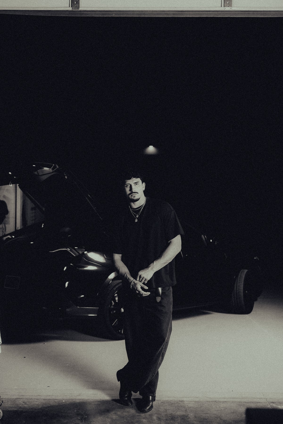 Model standing in a garage in the black classic crew tee
