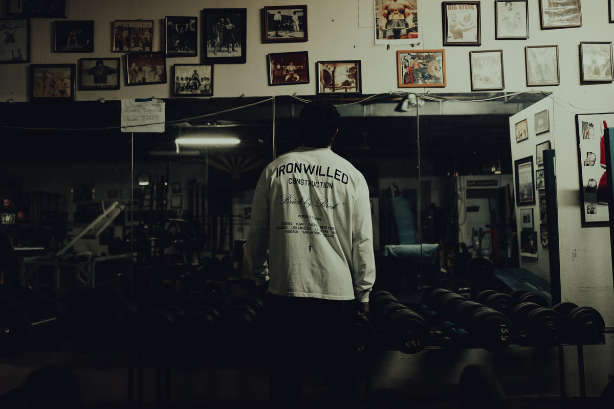 Back view of an athlete in the white Brick by Brick long sleeve inside a boxing gym