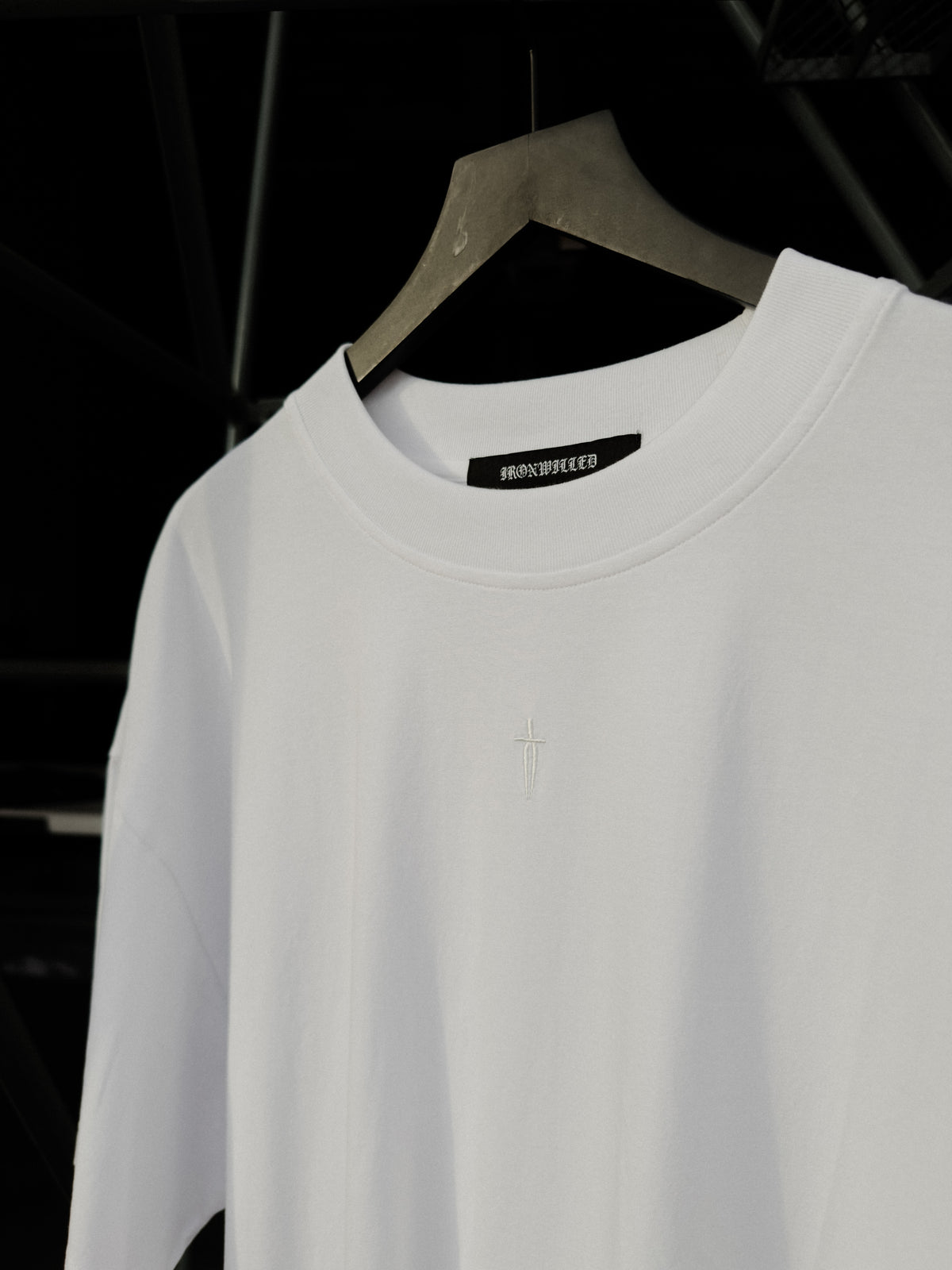 Dagger embroidery at the neck of the white tee