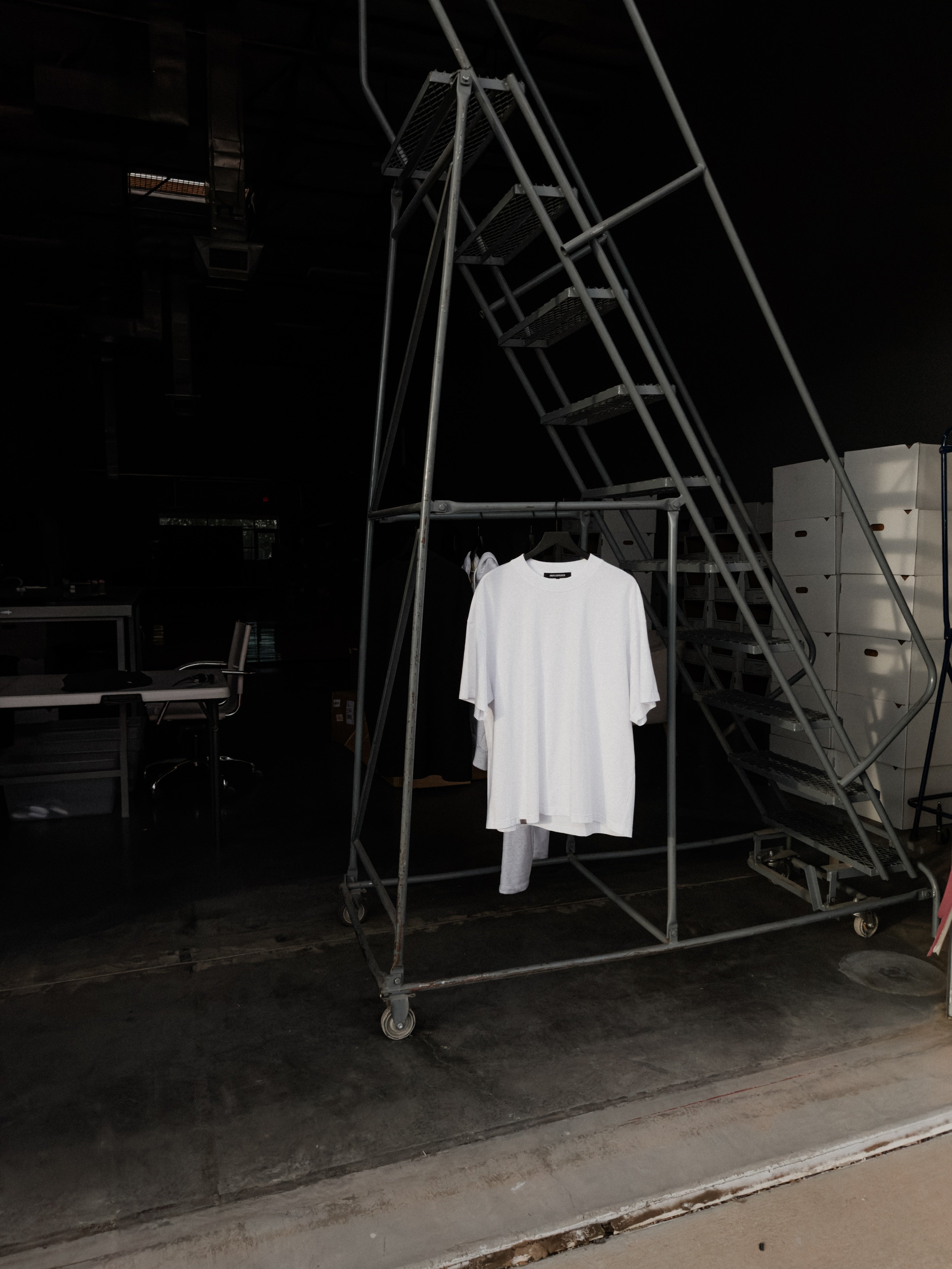 White classic crew tee hanging on a rolling rack