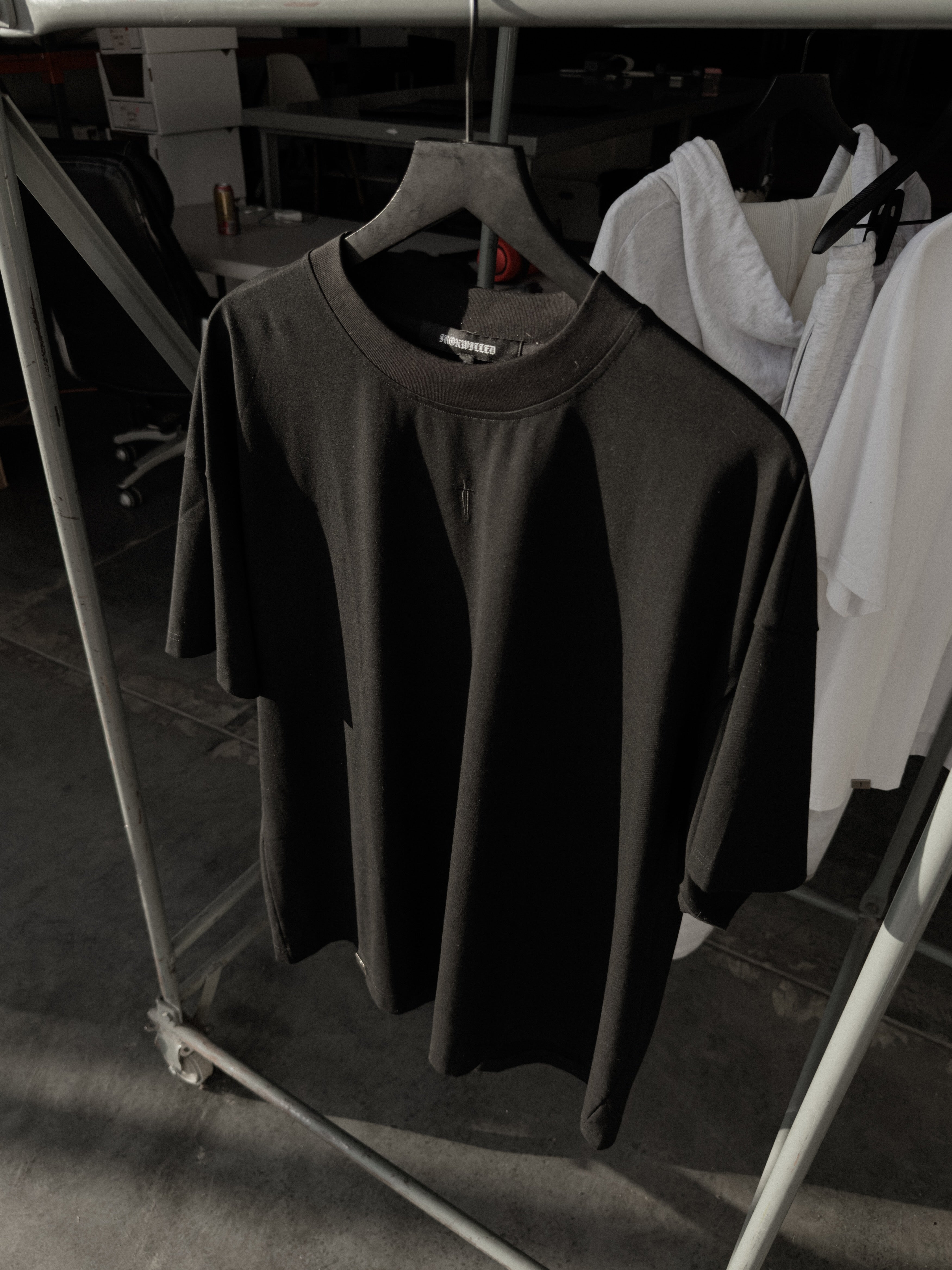 Black classic crew tee on a hanger, dagger embroidery at the neck