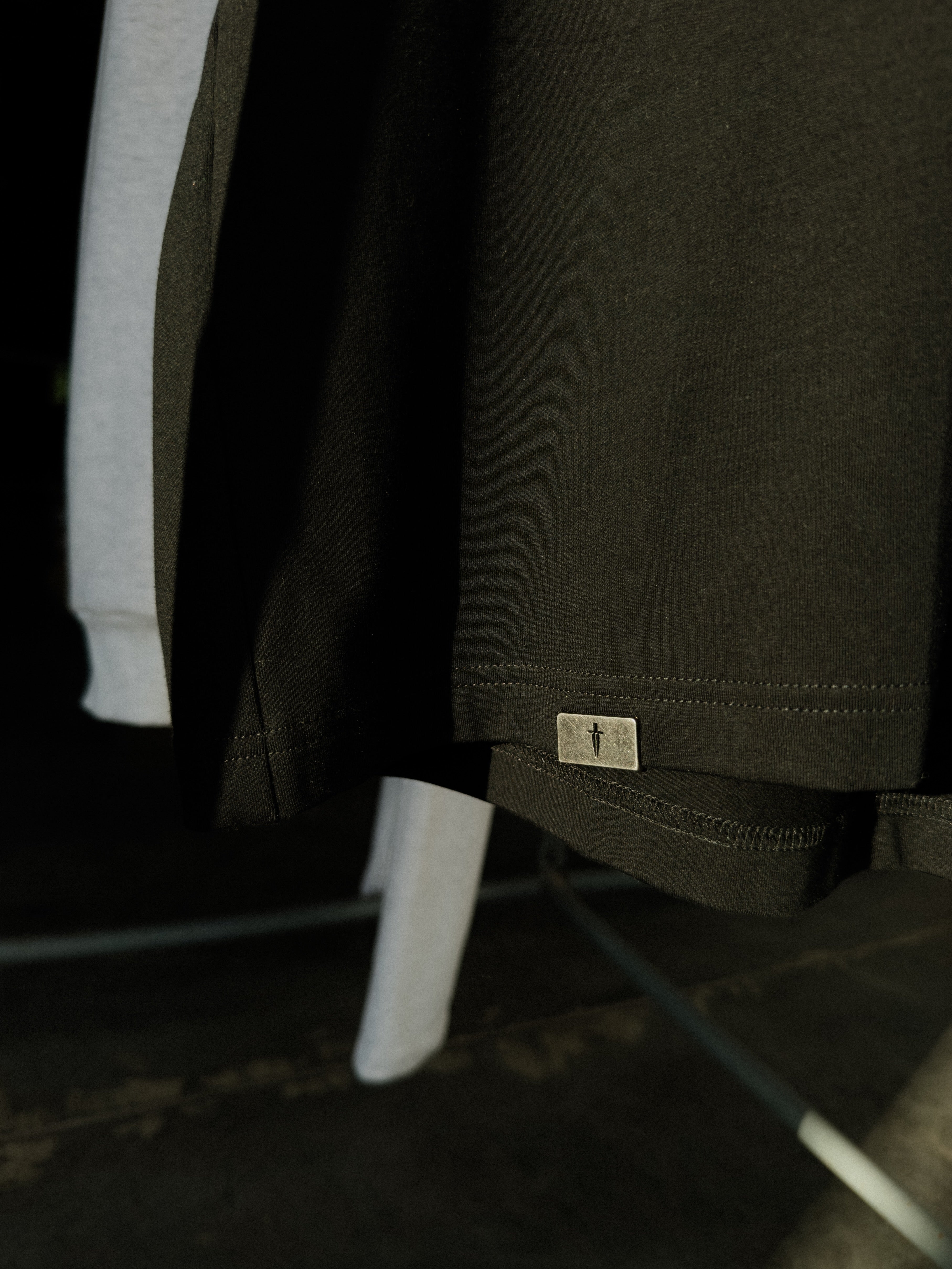 Signature metal tab at the bottom hem of the black tee