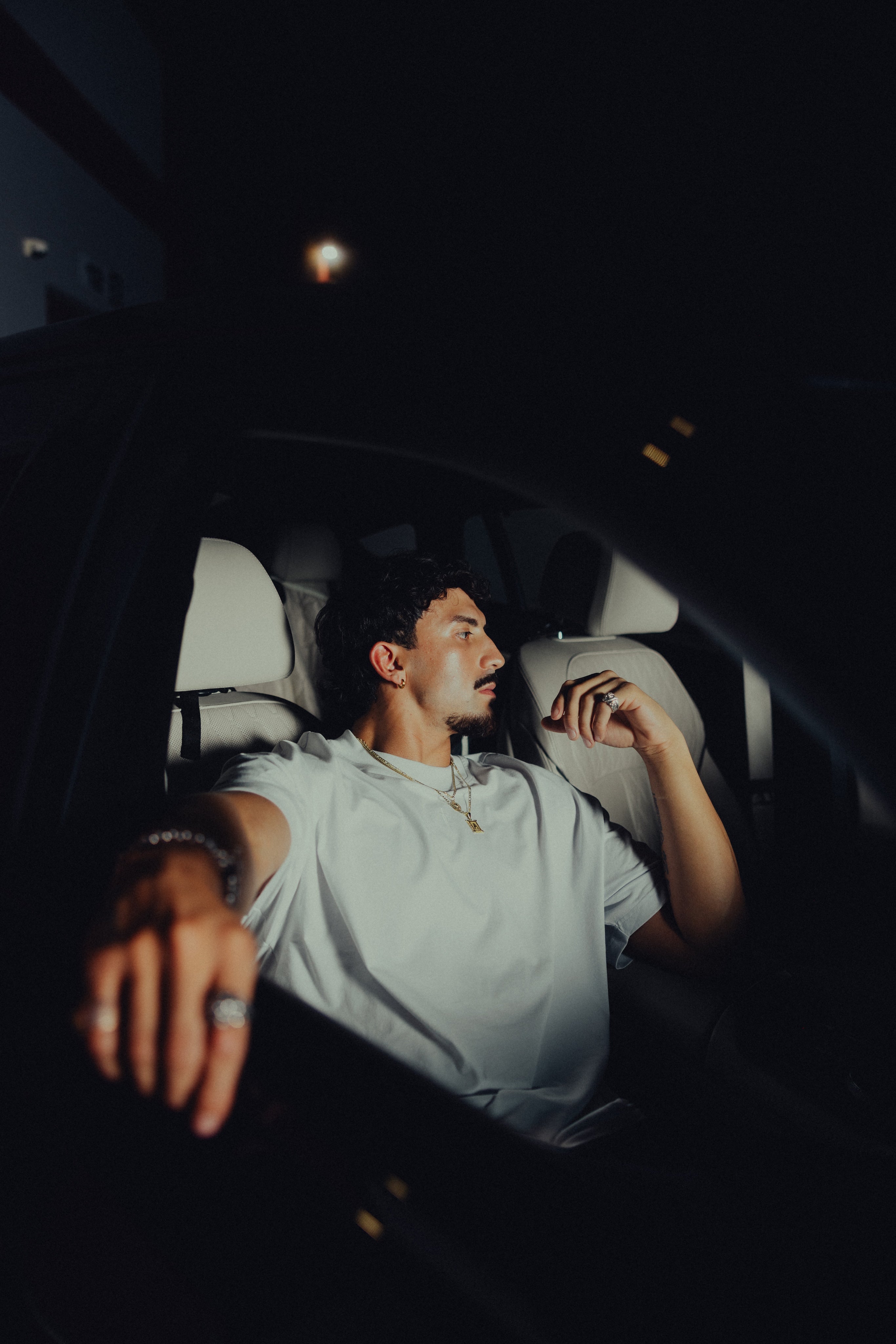 Model in the white classic crew tee seated in a car