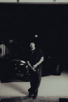 Model standing in a garage in the black classic crew tee